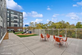 a patio with red chairs and a table in front of a building